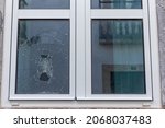 Cracked glass in a plastic vacuum window frame. A damaged window due to vandalism, natural disaster, or accident.