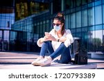 Small photo of Full length shot of careworn businesswoman wearing face mask for prevention and text messaging while on the street.