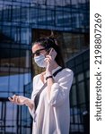 Small photo of Careworn woman using smartphone and walking outdoors in city during pandemia. Attractive female wearing face mask and plastic gloves.