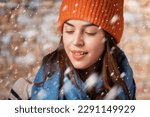 Close-up of beautiful smiling woman standing in snow . Blond haired woman wearing knit hat and scarf. Winter clothes, Copy space. 