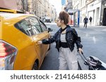 Young African American woman wearing black leather jacket in yellow taxi cab