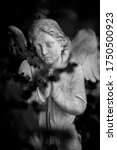 Small photo of Sad angel. Ancient stone statue with a sweet expression as symbol of unspeakable sadness and death. Black and white image.