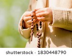 Close up young girl praying with wooden rosary. Horizontal image.