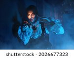 Small photo of A bloodthirsty vampire aristocrat standing in the castle and looks at a candle in his hands in darkness. 19th century style. Halloween.