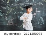 Clever kids. Portrait of a cute smart little girl in white shirt and glasses standing at the blackboard with chemical formulas with teacher's pointer in her hand. Education. 