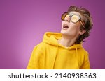 Small photo of Portrait of a funny surprised teen boy in bright yellow hoodie looking up with surprise and excitement. Bright purple background with copy space. Education. Youth lifestyle, success. Emotions.