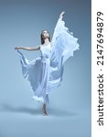 Small photo of A young graceful ballerina in a delicate white dress flies in a jump. Ballet, dance inspiration. Full-length studio portrait.