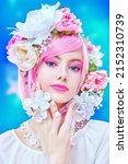 Small photo of Gorgeous girl with bright pink make-up poses in colored pink wig and flower wreath on head. Blue studio background. Beauty, makeup and hairstyle.