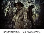 Halloween. A scene of horror, when an evil terrible Scarecrow with a bag on his head, in a sackcloth vestment and a black hat, stands in the thicket of the night forest. Horror, thriller.