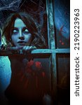 Small photo of Horror scene. A scary ghost girl looks out of the window of an old abandoned house. Haunted house. Halloween.