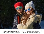 Joyful young man and a girl are having a walk in a winter park on a sunny day. Happy winter day. Winter activities. Fashion.