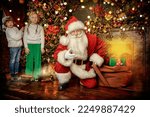 Two surprised kids with merry Santa Claus in a beautiful Christmas setting. Celebration of Christmas and New Year. 