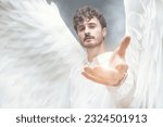 Small photo of The male guardian angel holds out his hand to the camera with calm and hope in his eyes. Heavenly light and white haze surround him.