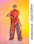 Small photo of Designer knitwear. Stylish fashion model posing in wide leg trousers, knitted poncho and knitted cap in studio in mixed color light. Bright colors. New fashionable demi-season collection.