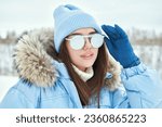 Sport in the mountains. Winter fashion. Portrait of a fashionable girl posing in blue ski suit against a snowy winter landscape.