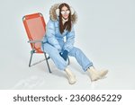 Winter active rest. A happy girl in a blue ski suit is resting in a ski resort. Winter fashion, clothes and accessories.