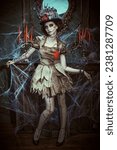 Small photo of A beautiful and treacherous young woman dressed as a voodoo doll stands in an old abandoned castle covered in cobwebs. Voodoo religion. Halloween.