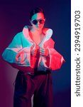 Small photo of Beautiful fashion model girl posing in stylish white jacket and big sunglasses. Studio shot against a dark background in mixed color light. Bright colors. Fashion and haute couture style.
