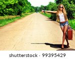 Pretty young woman hitchhiking along a road.