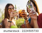 Cheerful group of millennial friends toasting alcoholic cocktails in the summer - people gathering cheering and drinking alcoholic drinks lifestyle concept