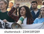 Small photo of Student Activist Leading Protest with Megaphone - A close-up of a young curly-haired woman leading a generic student protest, rallying her peers with passion and a megaphone