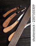 new professional hoof knives with  rasp for trimming horsy foot against black wooden background. horse hoof care concept