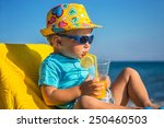 Small photo of Amusing kid drinks juice from tubule against sea in sunny day