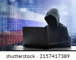 Russian hacker at laptop. Malware and virus danger from Russia. Man in hoodie and dark mask hacking. Dark net and cyber crime. Identity theft. Criminal at work. Troll army.
