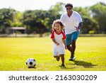 Small photo of Father and son play football. Dad and little boy play soccer. Young active family enjoy sunny summer day outdoor. Healthy sport for kids. Football game club.
