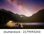 Small photo of Family camping under starry night sky. Milky way watching. Camp bonfire with kids. Travel and hiking with young children and dog. Group of people next to tent in national park. Star gazing.