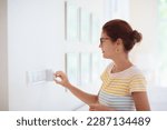 Small photo of Woman adjusting thermostat. Central heating. Comfortable home temperature. Female setting room climate control regulator. Cooling on hot summer day. Indoor air conditioning.