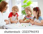 Small photo of Family playing board game at home. Kids play strategic game. Little boy throwing dice. Fun indoor activity for summer vacation. Siblings bond. Educational toys. Friends enjoy game night.