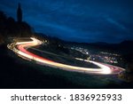 Long exposure - Car's Lights on the asphalt, at night on a mountain road, illuminated by the moon begins to rise over the horizon, a car making a turn, leaving behind a trail of light in the Mountains