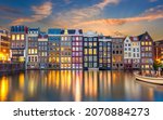 Old houses of Amsterdam in the evening. The houses stand in the water and have a beautiful reflection at night. Touristic district Damrak. These houses are famous all over the world. Amsterdam, Hollan