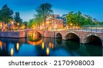 Romantic Amsterdam lit the lights. Evening panoramic view of the famous historic center with lantern lights, bridges, canals and cute Dutch houses. Amsterdam, Holland, European travel. Panoramic image
