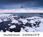 Kirkjufell mountain, Iceland. Winter landscape. The mountain and the ocean. Snow and ice. A popular place to travel in Iceland.