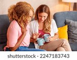 Small photo of Two women having fun spending leisure time together at home, drinking coffee and reading symbols from the cup afterwards, telling fortune
