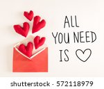 All You Need Is Love message with red heart cushions coming out of an envelope