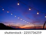 Small photo of Festoon string lights decoration at the party event festival against sunset sky. light bulbs on string wire with copy space. Outdoor holiday background