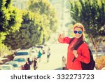 Beautiful smiling young woman with sunglasses and backpack in San Francisco city on a sunny warm autumn day. Positive emotions face expression. Instagram style yellow filter image
