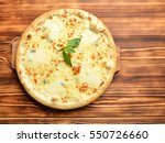 Four cheese pizza quattro fromaggi with basil leaf on a rustic wooden board background