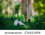 Woman walking barefoot on the green grass, shoes in focus, shallow DOF