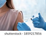 Small photo of Male doctor holding syringe making covid 19 vaccination injection dose in shoulder of female patient. Flu influenza vaccine clinical trials concept, corona virus treatment side effect, inoculation.