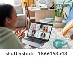 Small photo of African teen girl talking with friends on distance video group conference call in bedroom. Mixed race teenager having fun chatting during virtual meeting at home communicating online lying in bed.