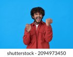 Small photo of Excited happy young indian man winner looking at camera showing yes gesture feeling happy about betting lottery win, winning prize, getting new job celebrating victory isolated on blue background.