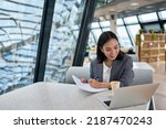 Small photo of Young Asian business woman employee or executive manager using computer looking at laptop and talking leading hybrid conference remote video call virtual meeting or online interview working in