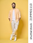 Small photo of Smiling happy confident rich indian man standing isolated on yellow background. Happy handsome ethnic guy looking at camera advertising products posing for vertical full length portrait.