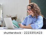 Small photo of Young business woman, female online teacher looking at laptop talking leading hybrid conference online remote video call, virtual distance class or webinar training presentation working in office.