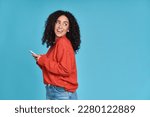 Young curious smiling happy pretty latin woman holding mobile phone, doing online shopping on cell, using apps on cellphone looking aside at copy space standing isolated on blue background.