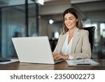 Happy mature business woman entrepreneur in office using laptop at work, smiling professional middle aged 40 years old female company executive wearing suit working on computer at workplace.